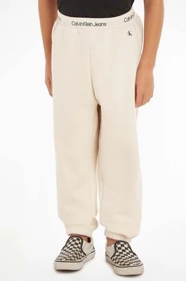 Zdjęcie produktu Calvin Klein Jeans spodnie dresowe dziecięce kolor beżowy gładkie