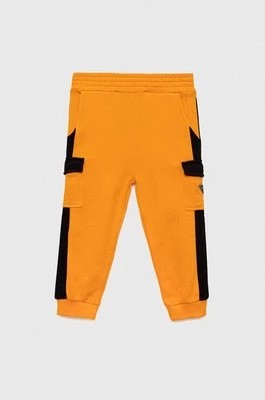 Zdjęcie produktu Guess spodnie dresowe bawełniane dziecięce kolor pomarańczowy wzorzyste