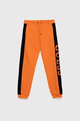 Zdjęcie produktu Guess spodnie dresowe bawełniane dziecięce kolor pomarańczowy z aplikacją